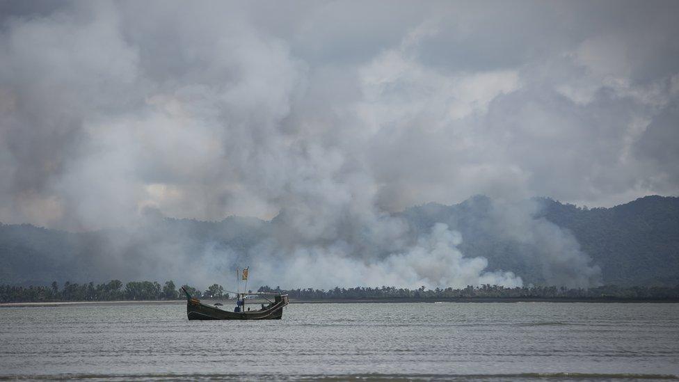 River in foreground and white smoke rising from the ground beyond