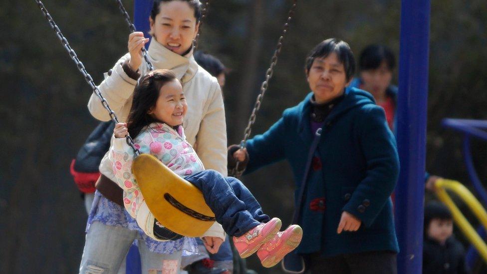 A mother pushes her daughter on a swing in Beijing, 2013.