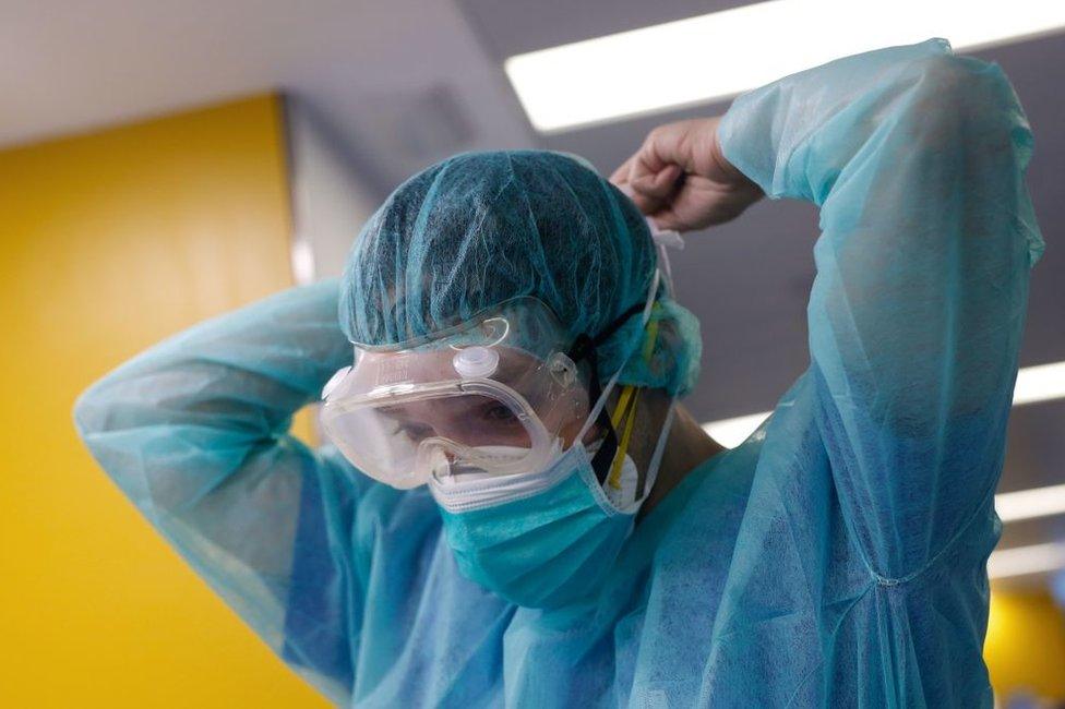 Health worker in Spain tying on face mask