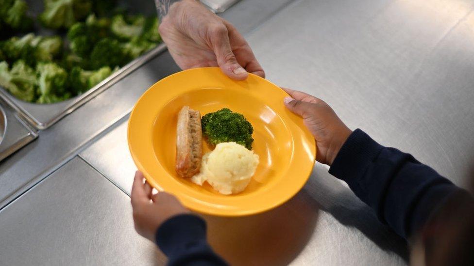 A school chef serves dinner to a pupil