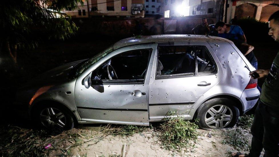 Palestinians inspect a car damaged in a bombing in Gaza City on 27 August 2019