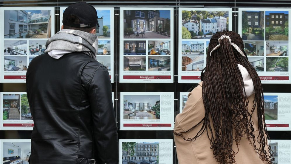 People looking in an estate agent's window