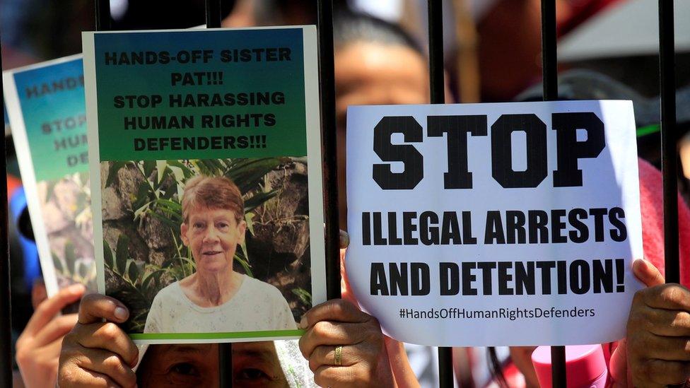 Supporters of Australian nun Patricia Fox, 71, hold placards while waiting for her release outside of the Bureau of Immigration headquarters in Manila