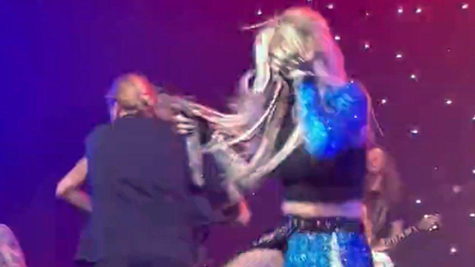 Screenshot taken from video with permission from the Twitter account of @Joelr_23 of singer Ava Max holding her face as security remove a fan who jumped onto the stage during her concert in Los Angeles, USA