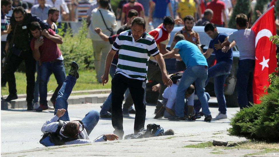 Supporters of Turkey's President Recep Tayyip Erdogan, who were staging a protest against a coup, clash with Turkish journalists near the Turkish military headquarters, in Ankara, Turkey, Saturday, July 16, 2016.