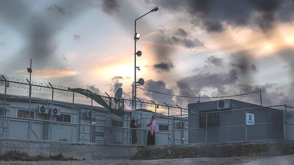 Women make phone calls inside the Moria refugee camp