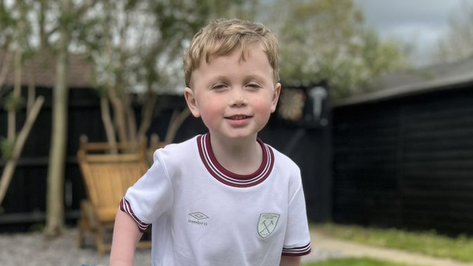 Jesse standing in his garden holding the crossbar of a small football goal