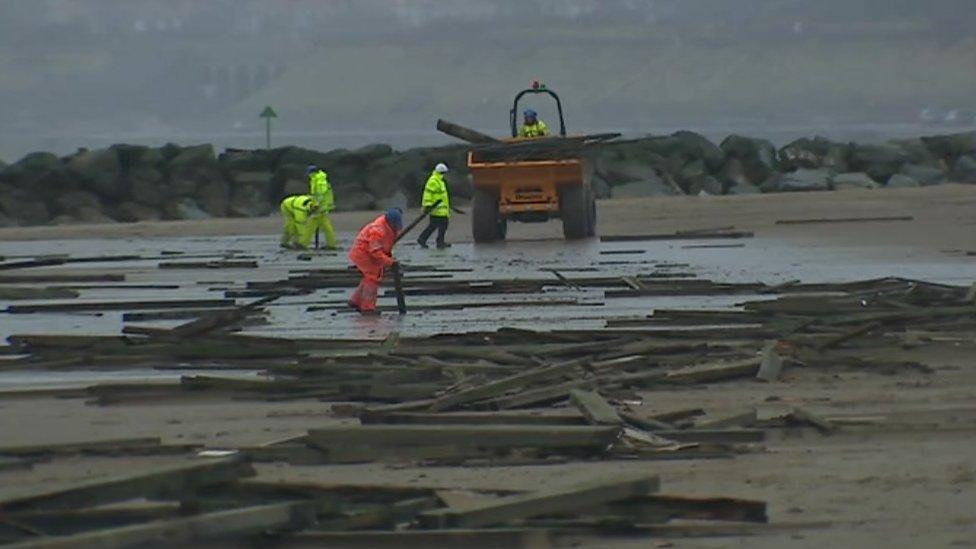 Engineers clean up the Colwyn Bay pier damage strewn across the beach