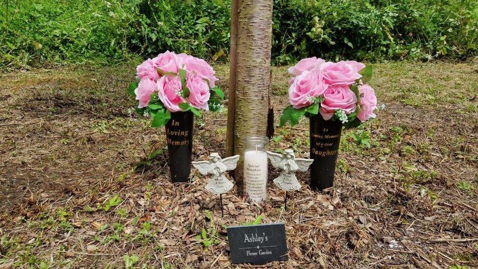 Flowers by a tree and mementos in memory of Ashley Dale