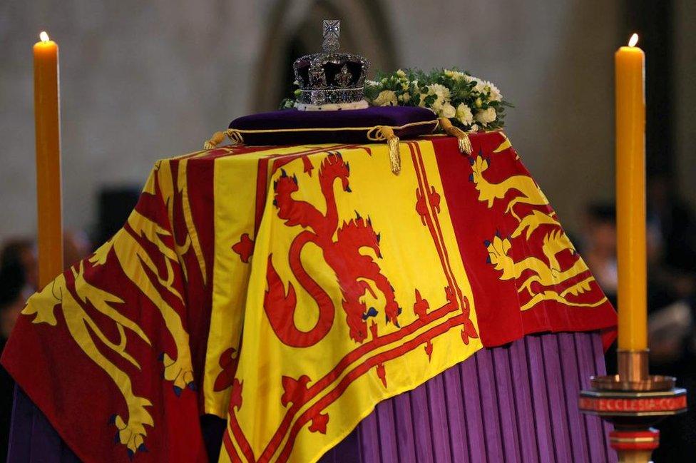 The Queen's coffin in Westminster Hall. with her crown resting on top and candles on either side