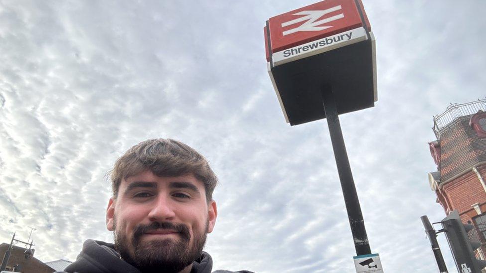 Jared Evitts in front of the sign to Shrewsbury