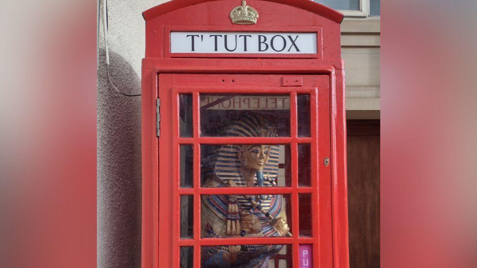 Model of Tutankhamun's sarcophagus inside a red phone box