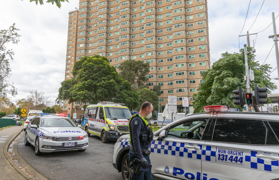 Police cars and officers outside one of the locked-down towers in Melbourne