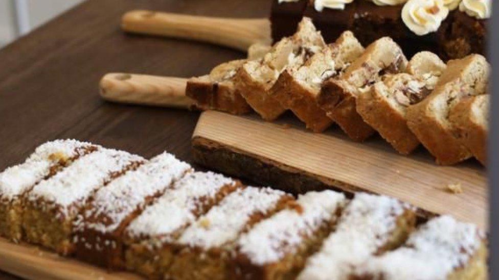 A selection of cakes laid out on a table top, some with icing on