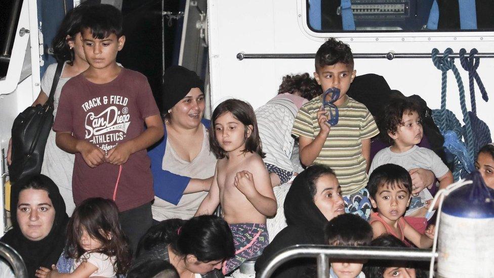 Italian Coast Guard and medical staff escort Iraqi Kurdish migrants off a Coast Guard patrol boat in the port of Crotone, Italy - 13 July 2018