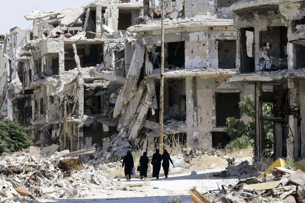 Women walk in between destroyed buildings in the Jouret al-Shiah neighbourhood of the central Syrian city of Homs (19 September 2016)