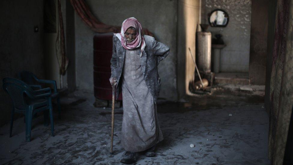 A Syrian man covered with dust from explosions