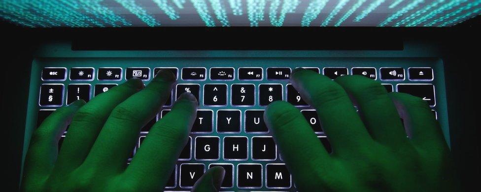 A man's hands typing on a laptop keyboard