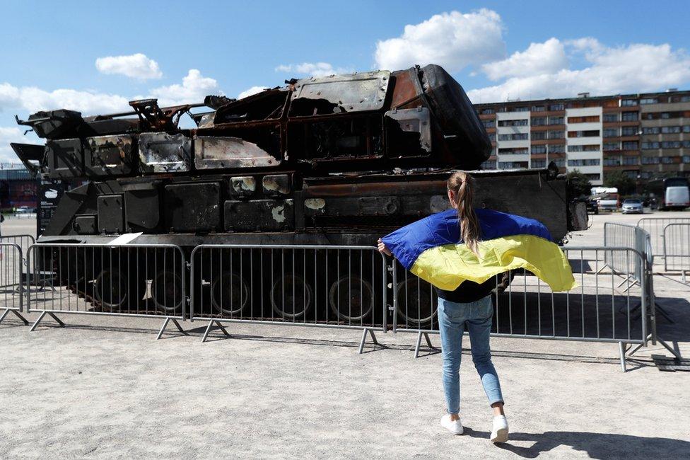 A woman holding a Ukrainian flag looks at Russian military equipment destroyed by the Armed Forces of Ukraine displayed in Prague, Czech Republic, on 11 July 2022