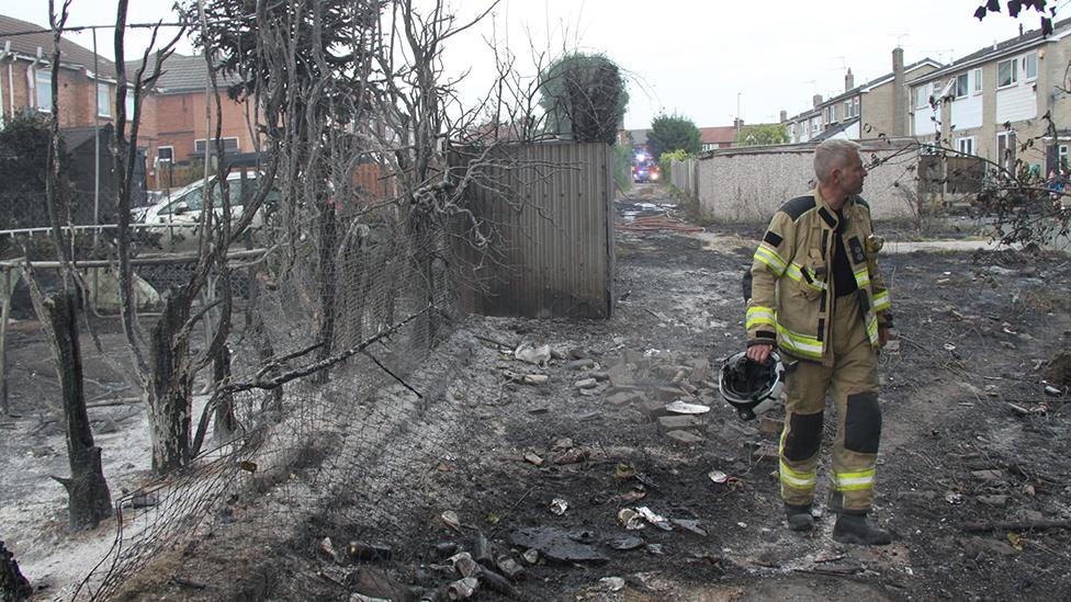 Firefighter walks through burnt out trees