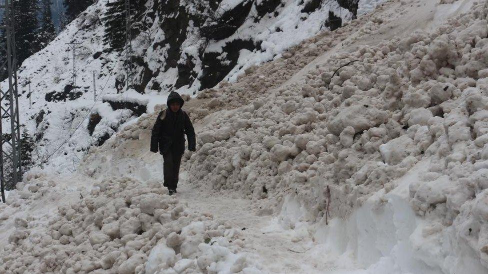 Boy walks in snow in Neelum valley - roads are cut off