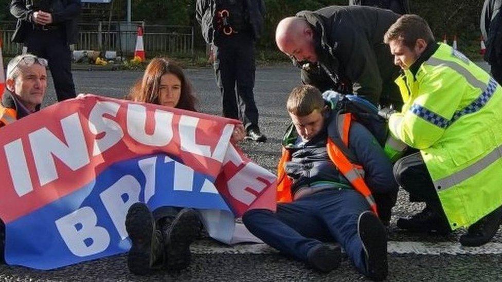 Police officers try to move protesters from the road