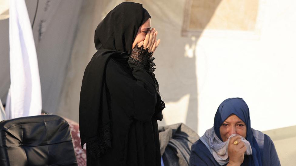 Two women grieve as they sit outside a make shift morgue where the bodies of Palestinians killed in Israeli bombardment are brought before burial, at the Shuhada Al-Aqsa hospital, in Deir el-Balah, in the central Gaza Strip on 6 November 2023