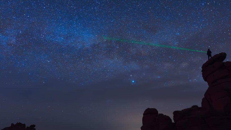 Green laser being shone in sky