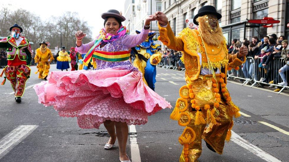 Performers dance down the street