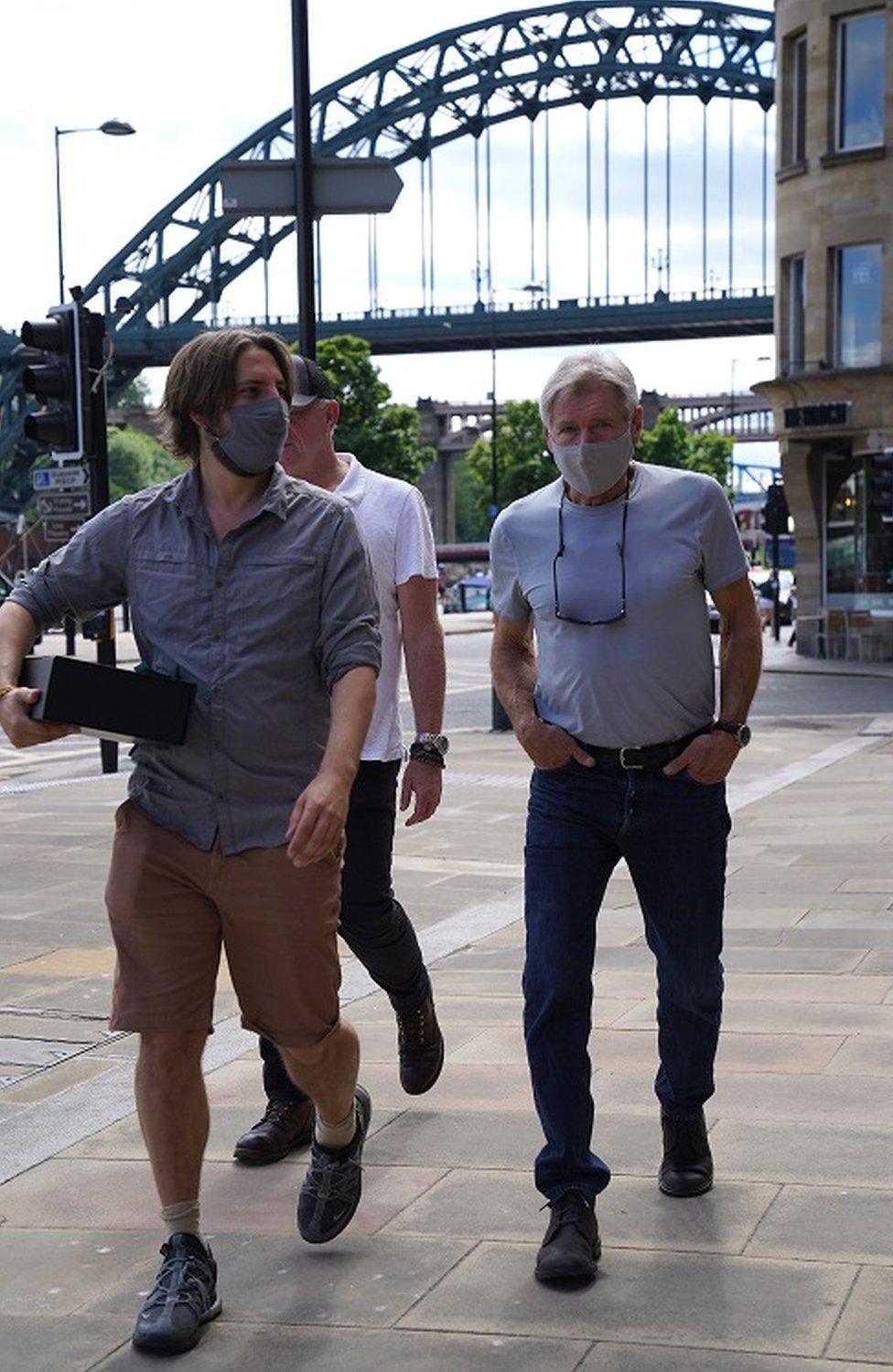 Harrison Ford, wearing a face mask, on Newcastle Quayside with the Tyne Bridge in the background