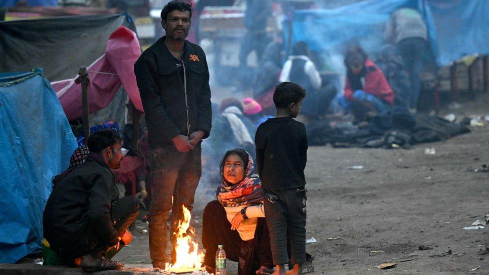 People sit next to a bonfire to keep themselves warm during a cold winter morning in New Delhi on January 2, 2024. (Photo by Money SHARMA / AFP) (Photo by MONEY SHARMA/AFP via Getty Images)