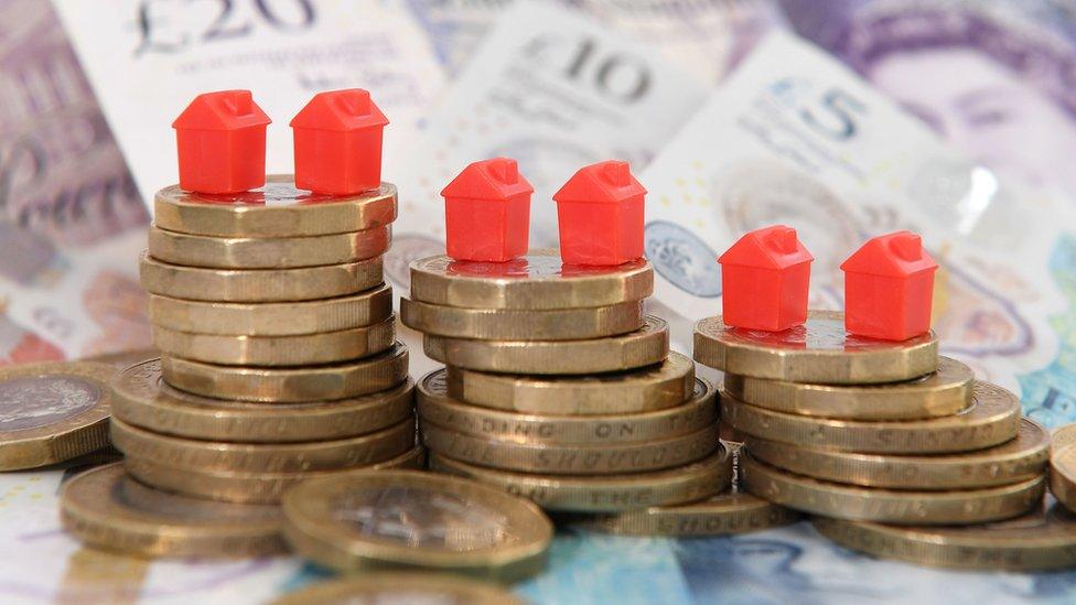 model houses on a pile of coins and bank notes