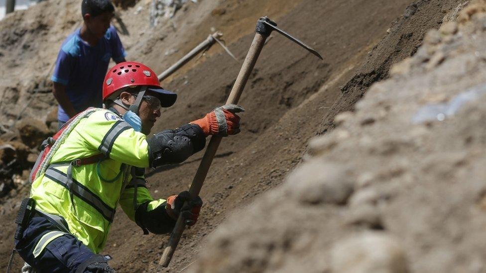 A rescue worker and resident dig into the earth in search of survivors after a mudslide in Santa Catarina Pinula, on the outskirts of Guatemala City, Friday, Oct. 2, 2015.