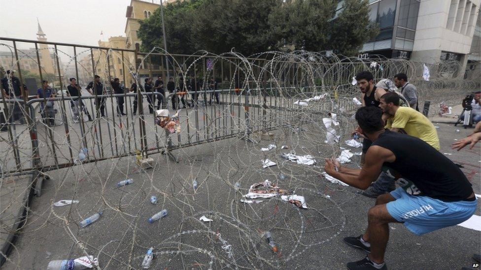 Lebanese anti-government protesters try to remove barbed wire that blocks a road leading to the parliament building on 9 September 2015