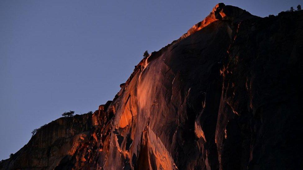 Water flowing off Horsetail Fall glows orange while backlit from the setting sun during the "Firefall" phenomenon in Yosemite National Park