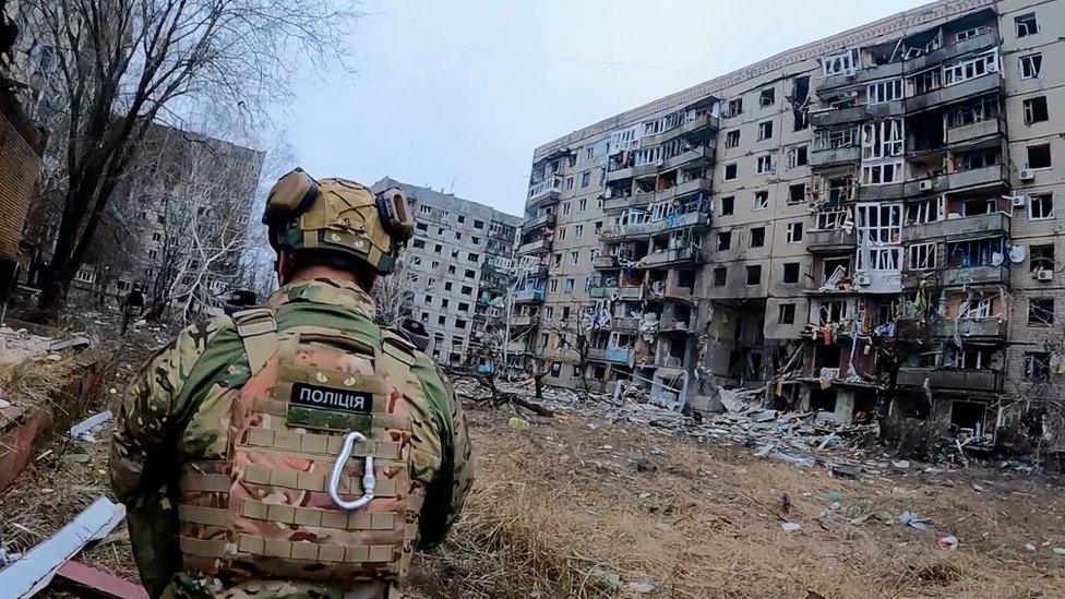 Man with destroyed building in the background