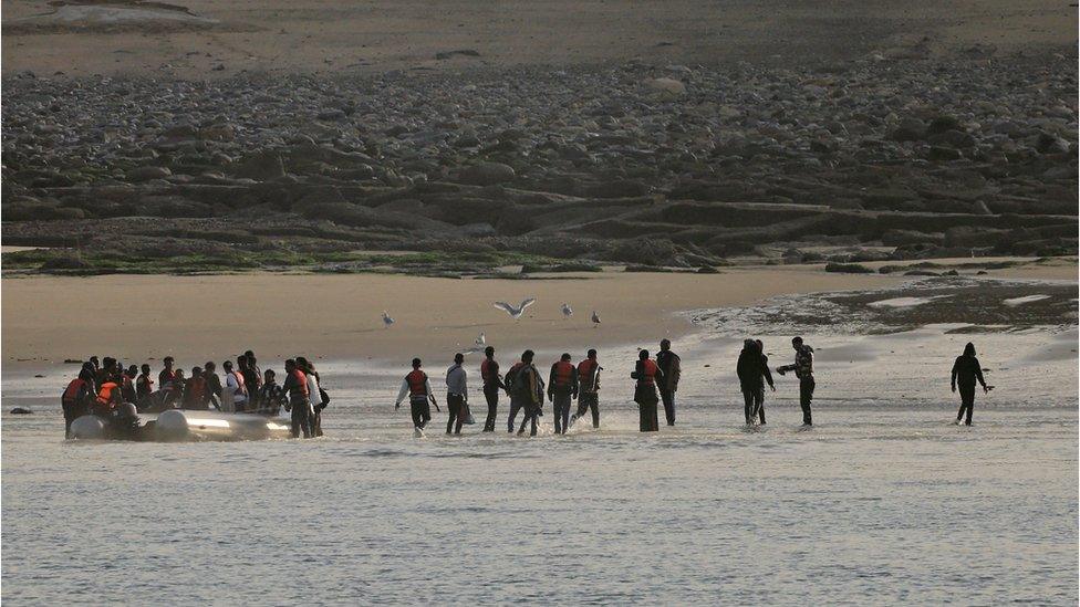 A group of migrants leave a dinghy after an unsuccessful attempt to cross the English Channel