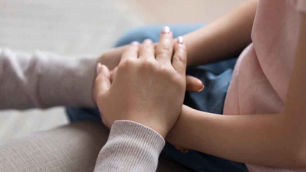 A woman holding a child's hands