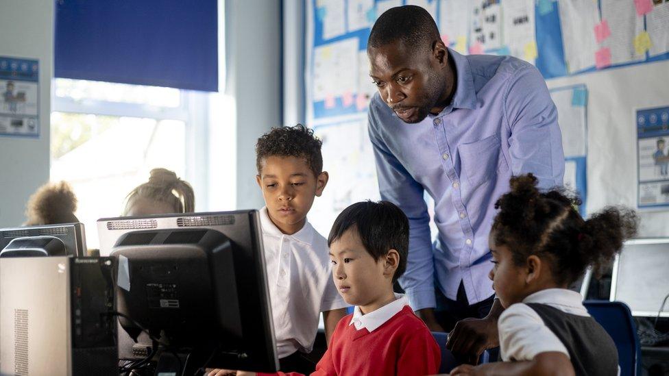 Male teacher helping IT pupils