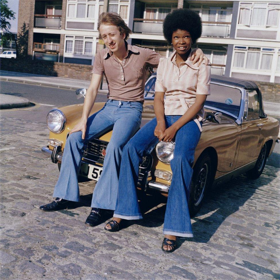 A couple sit on the bonnet of an MG in London, 1970s