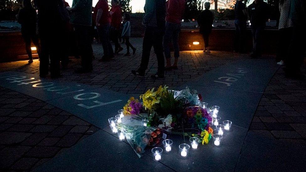 Candles wrap around a collection of flowers laid at the memorial