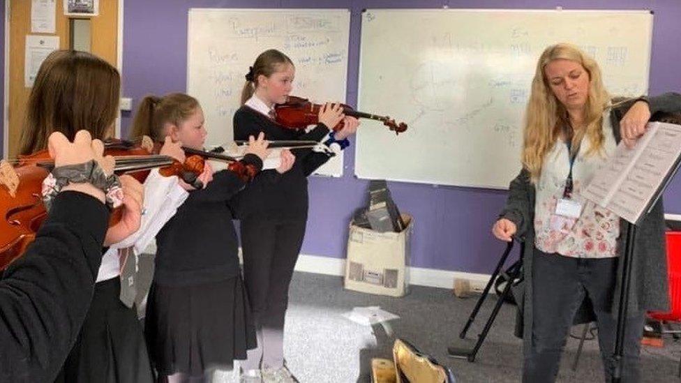 Hannah Jeans-Wells teaching three students the violin