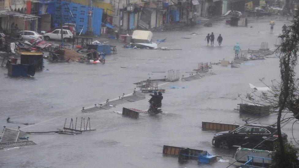 People wade through floodwaters in Puri after Cyclone Fani hit