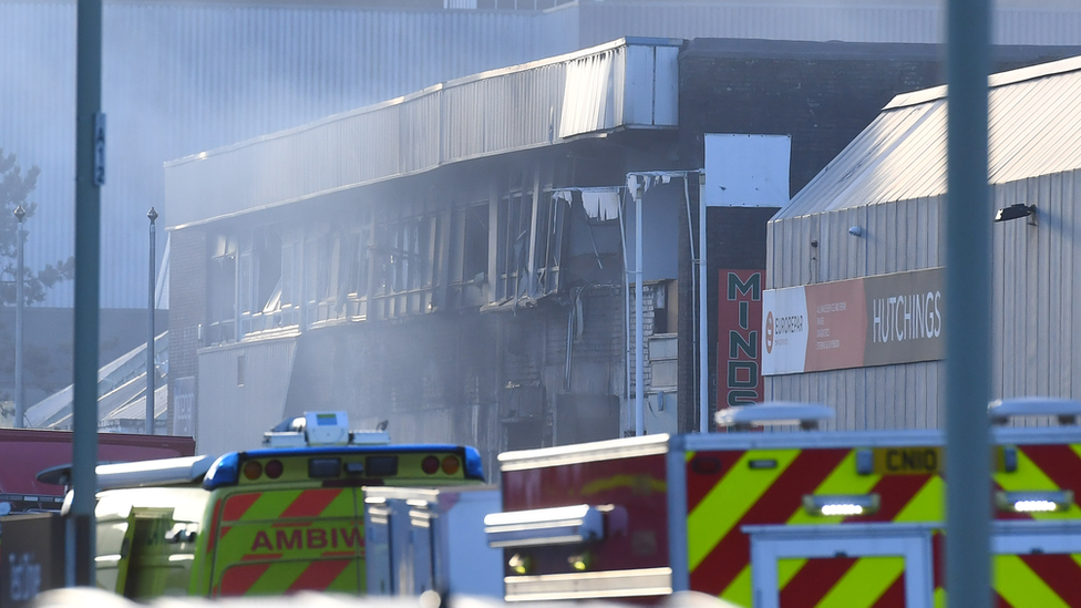 Burnt out gym building with emergency service vehicles in front