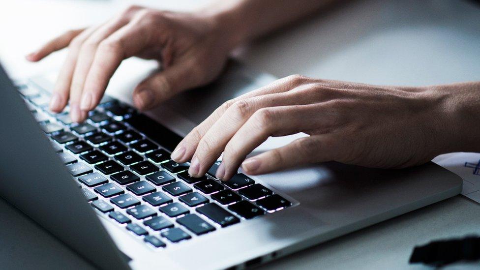 Hands typing on a laptop keyboard