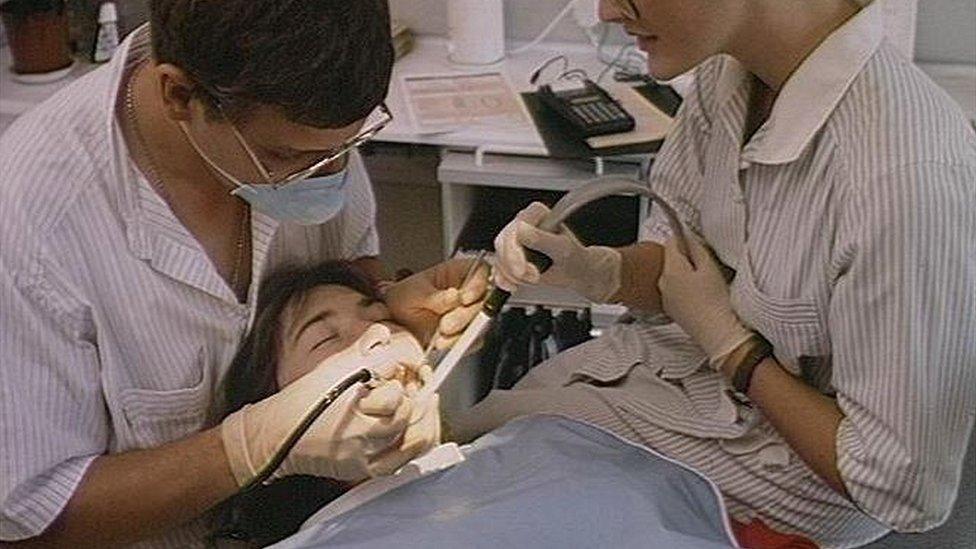 Dentist and nurse examining a female patients teeth.