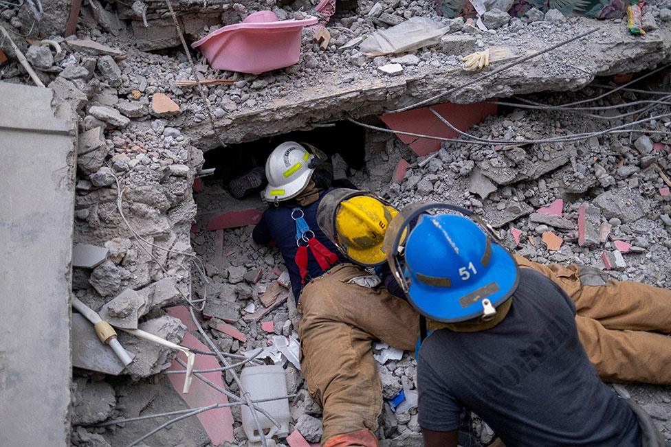 Haitian firefighters search for survivors, under the rubble of a destroyed hotel, in Les Cayes