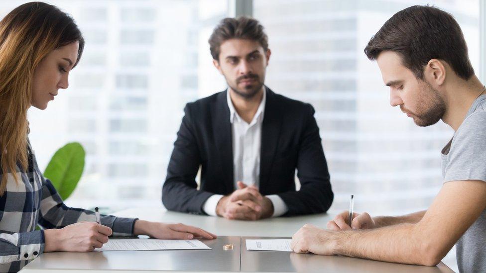 Couple signing decree papers getting divorced in lawyers office - stock photo