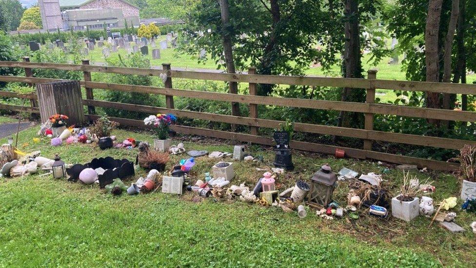 Trinkets strewn across the grass in the memorial garden