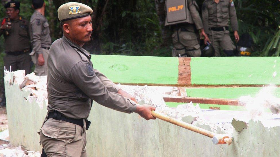 An Indonesian official takes a sledgehammer to a church wall during the demolition of several churches by the local government in Singkil, Aceh province 19 October 2015.